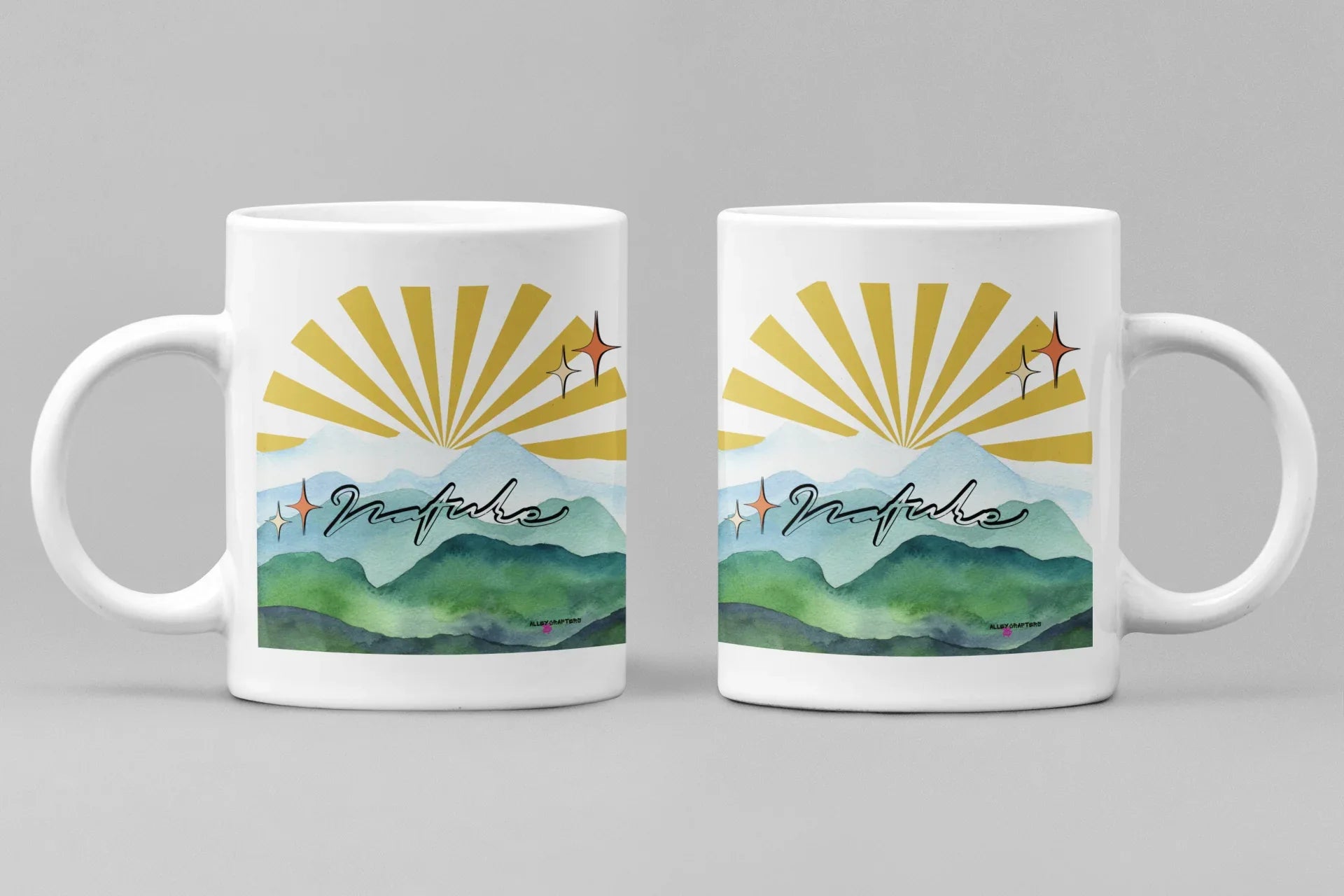 White coffee mug with sunrise rays and mountain landscape graphic on front