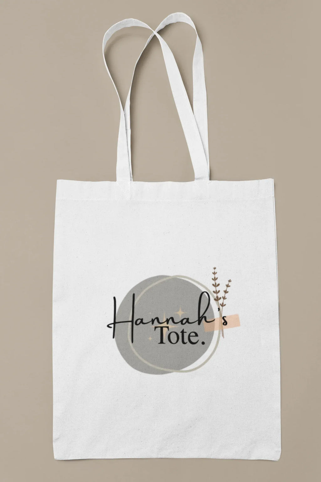 White cotton tote bag with circular “Hannah’s Tote” print and small botanical sprig