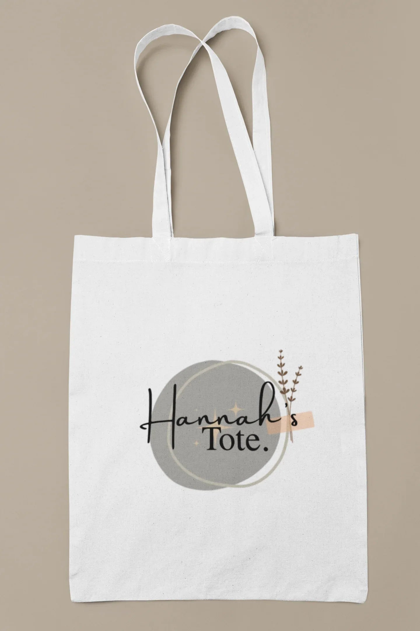 White cotton tote bag with circular “Hannah’s Tote” print and small botanical sprig