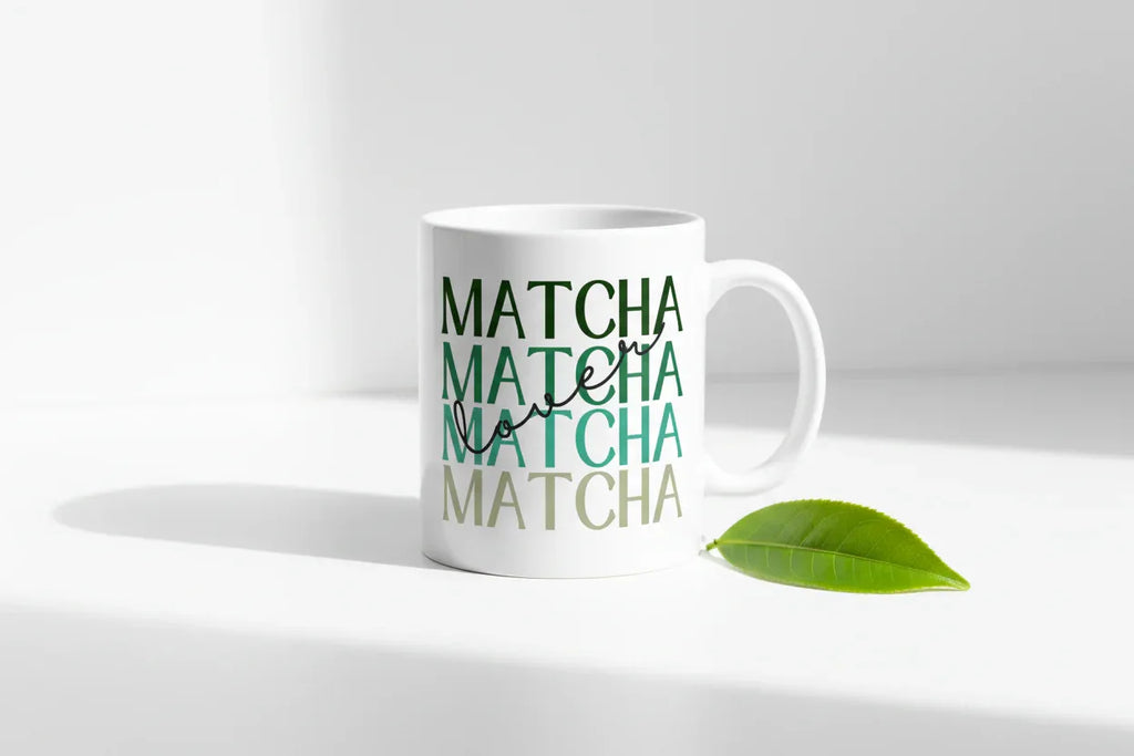 White ceramic matcha mug with green MATCHA design, leaf on surface