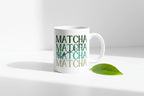 White ceramic matcha mug with green MATCHA design, leaf on surface