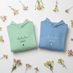 Set of mint green and blue hoodies, each with drawstring hood and “delulu vibes”