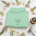 Mint green pullover hoodie with drawstring hood and “delulu vibes” graphic