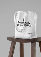 White tote bag with 'Emotionally Out of Office' slogan on front.