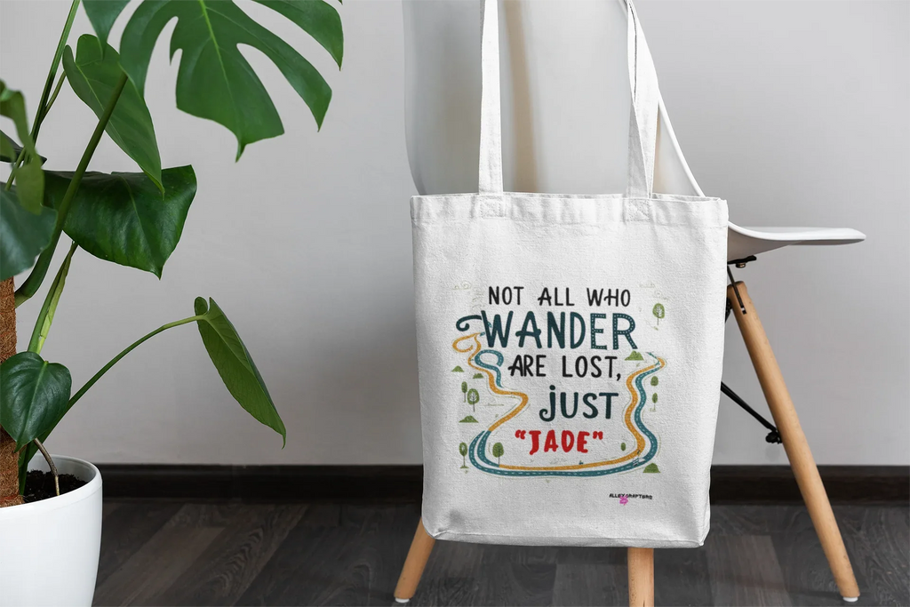 White canvas tote bag with long handles, centered front quote graphic in colorful ink