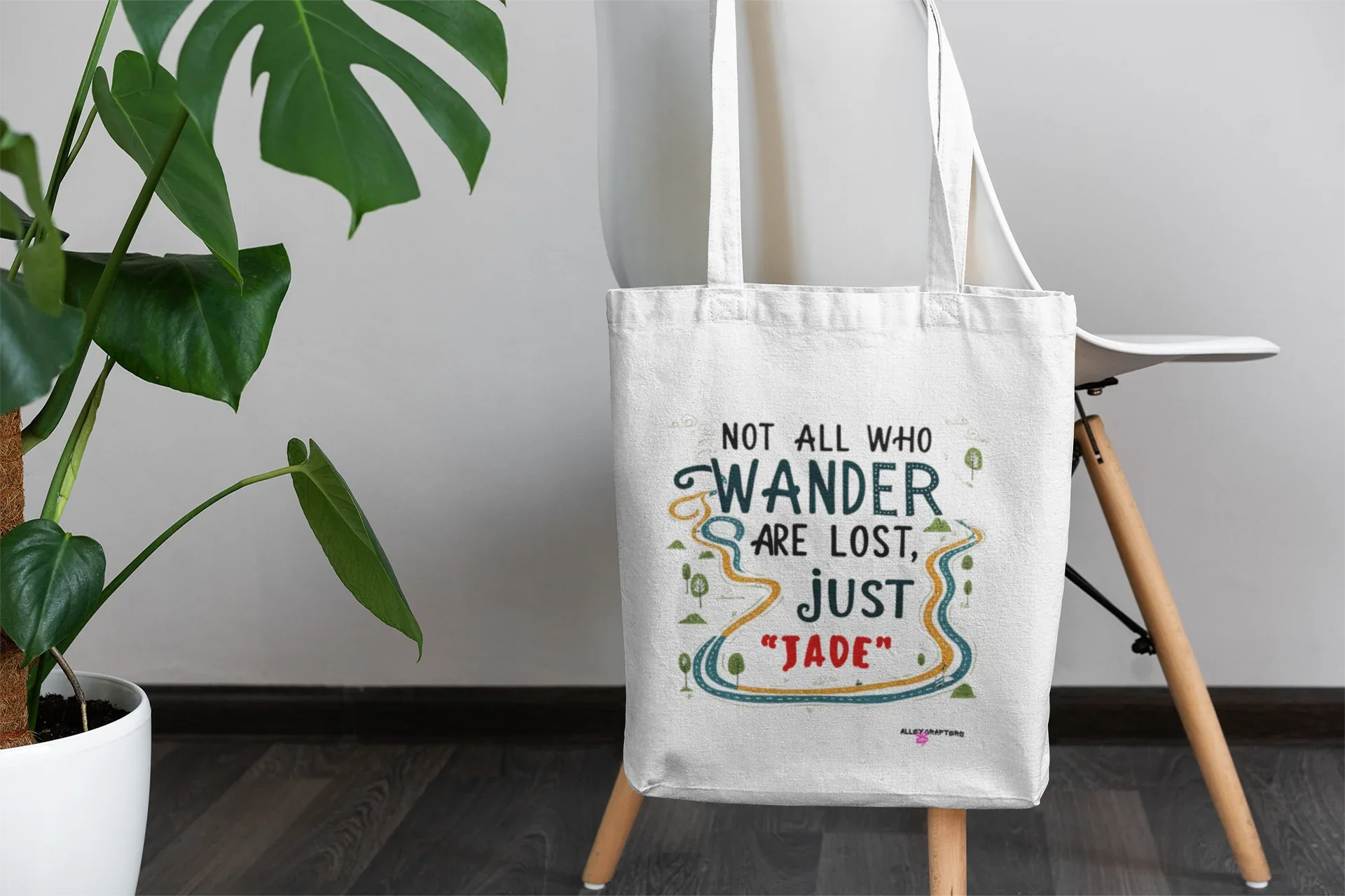 White canvas tote bag with long handles, centered front quote graphic in colorful ink