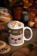 White coffee mug with cat face and 'Hello!' design, filled with coffee and cream