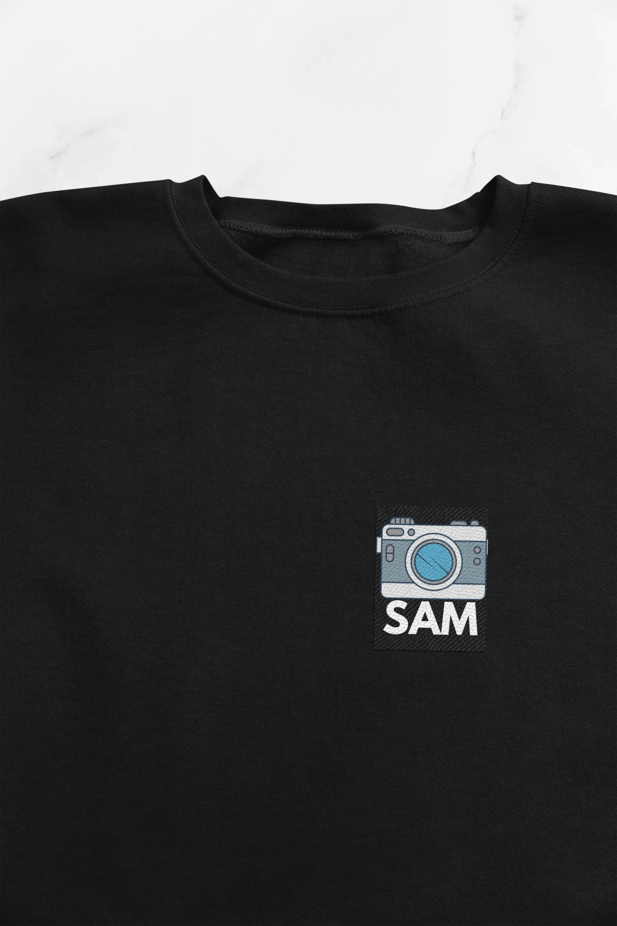 Black sweatshirt with embroidered camera icon and name SAM on left chest
