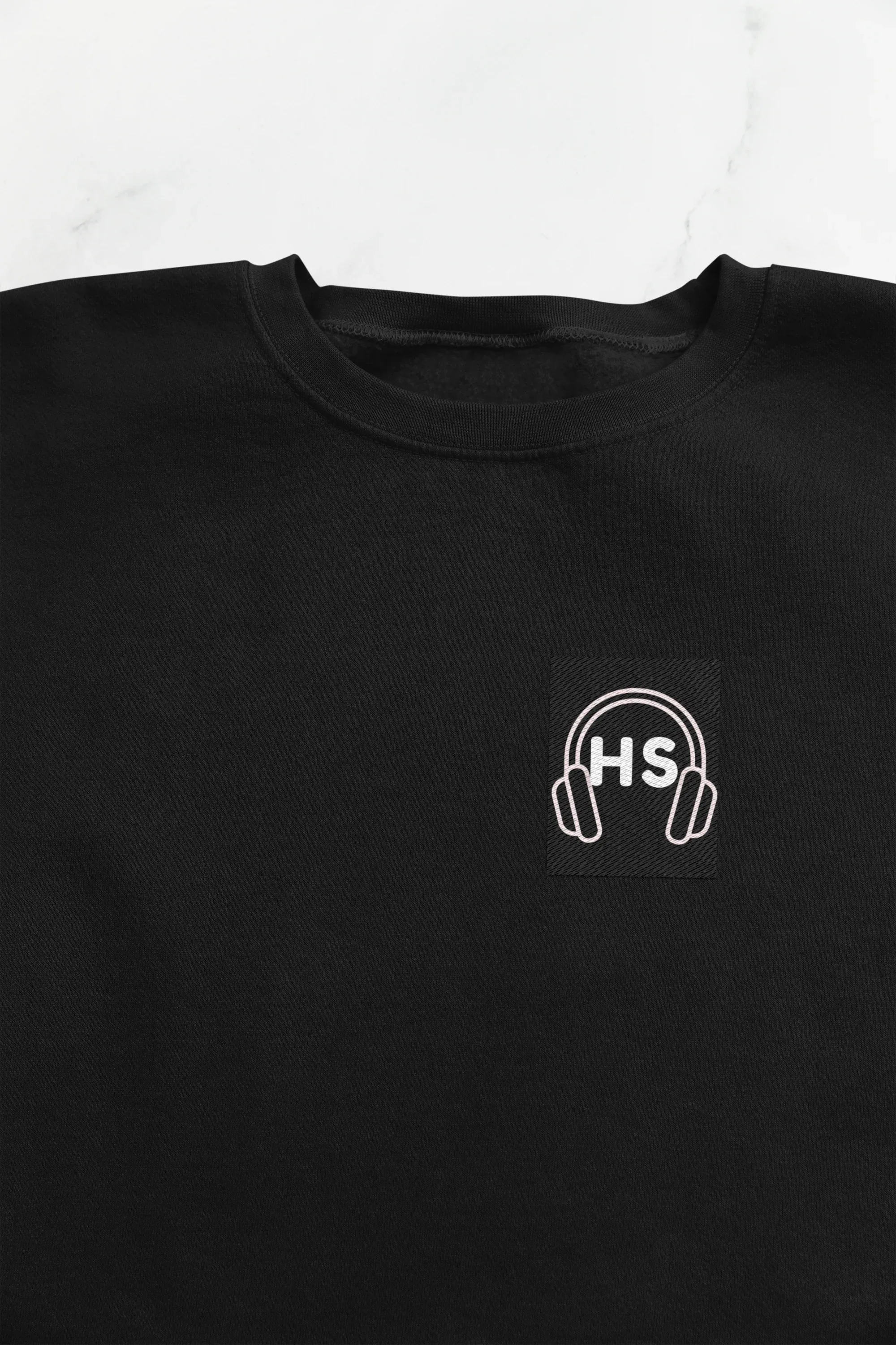 Black sweatshirt close-up: embroidered headphone logo on chest