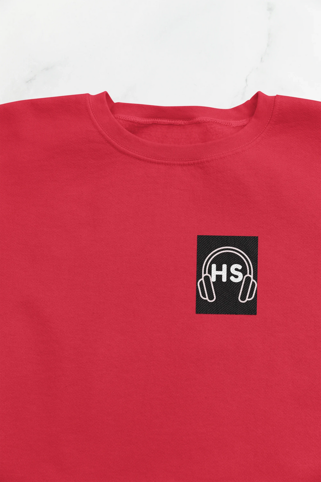 Red sweatshirt close-up with embroidered headphone logo on chest