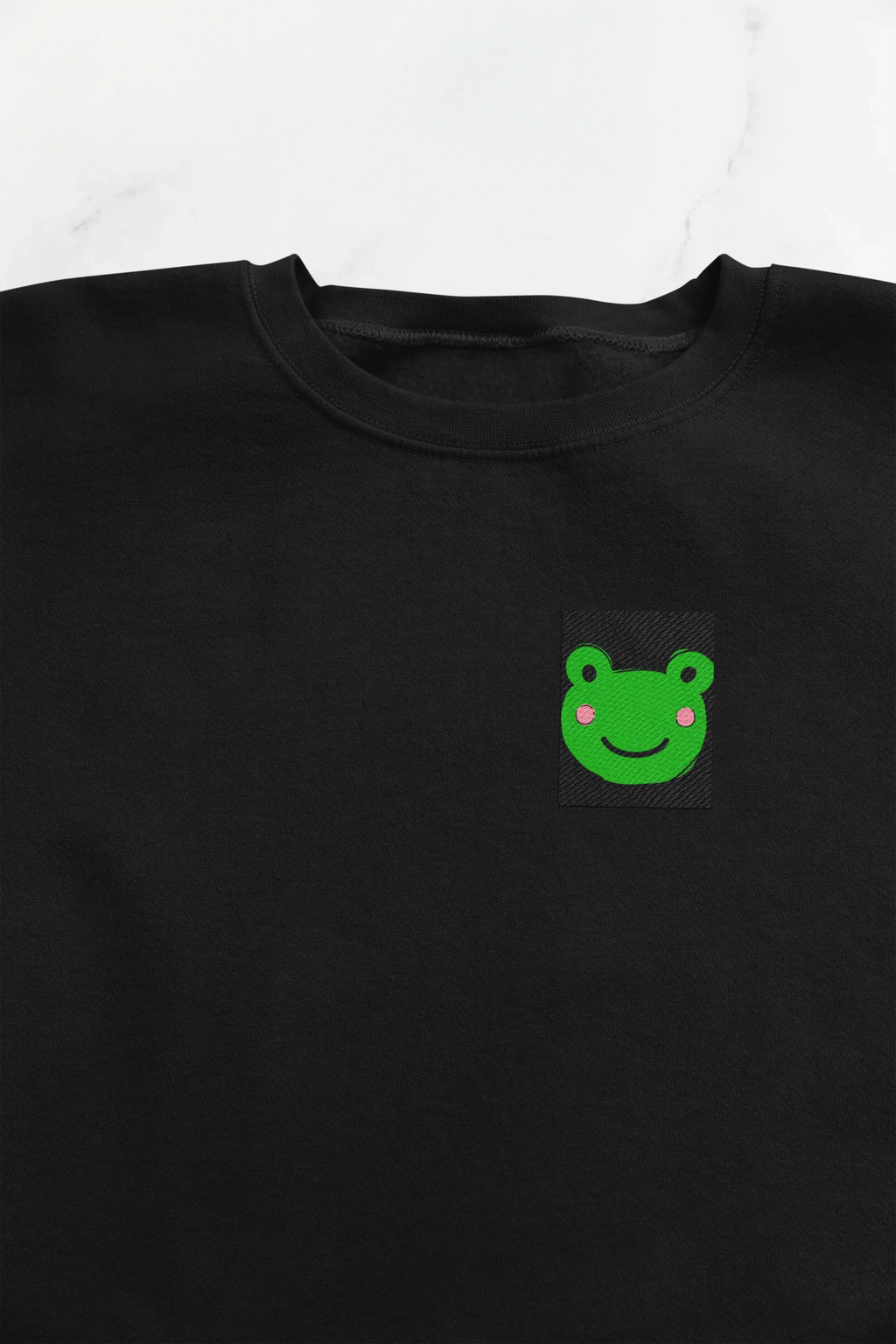 Black sweatshirt front with small green frog face embroidery on the left chest