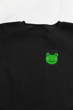 Black sweatshirt front with small green frog face embroidery on the left chest