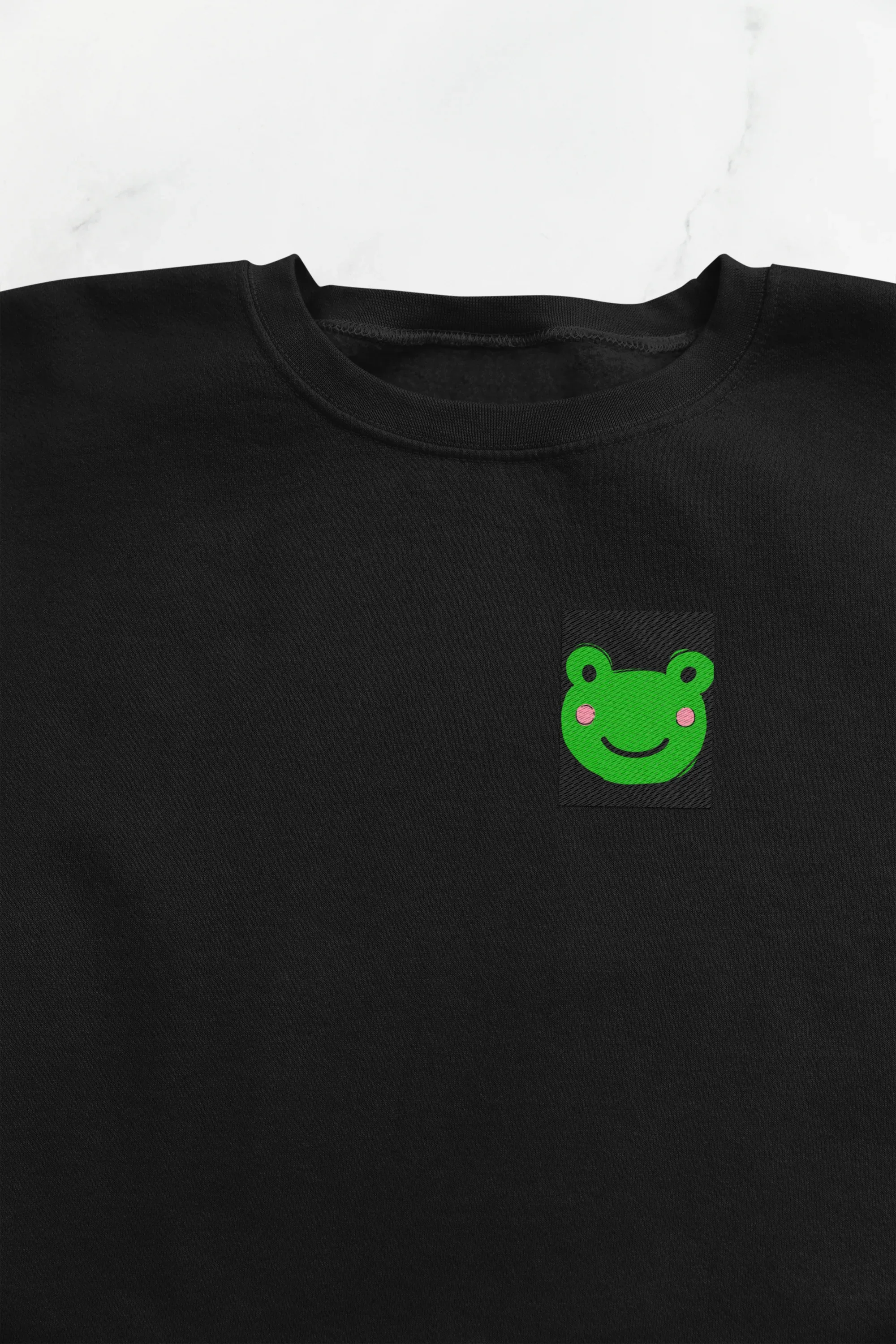 Black sweatshirt front with small green frog face embroidery on the left chest
