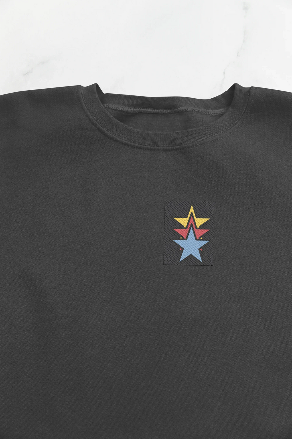Black unisex sweatshirt close-up showing crew neck and star embroidery