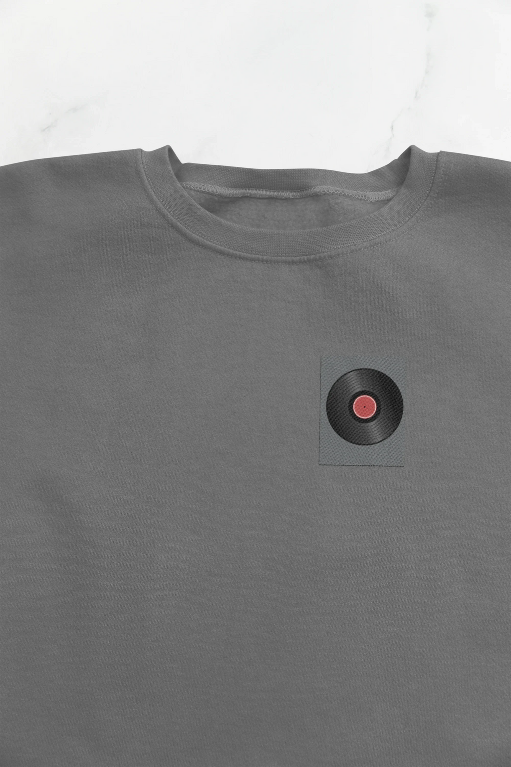 Embroidered record player patch on dark heather sweatshirt chest