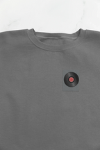 Embroidered record player patch on dark heather sweatshirt chest