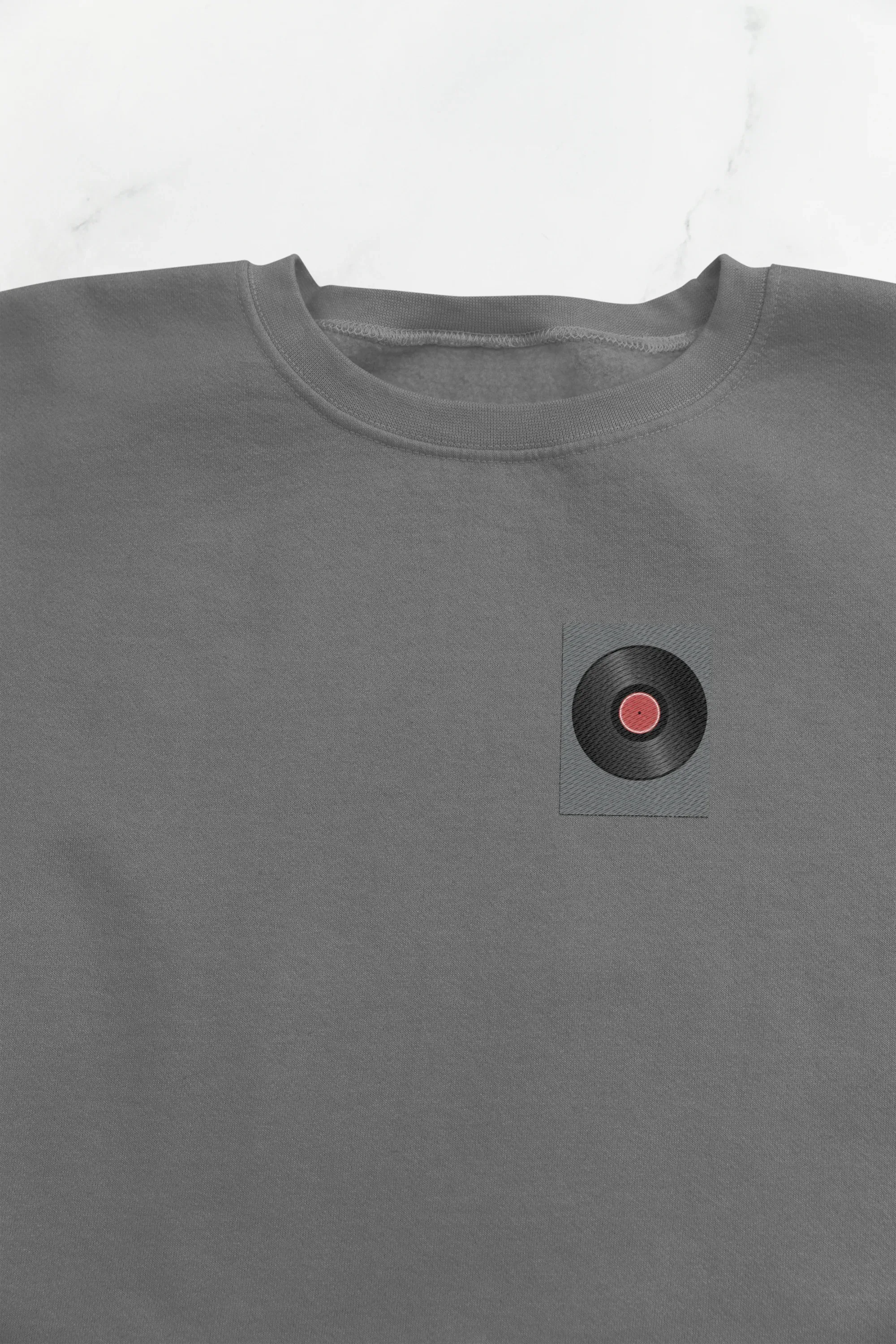 Embroidered record player patch on dark heather sweatshirt chest