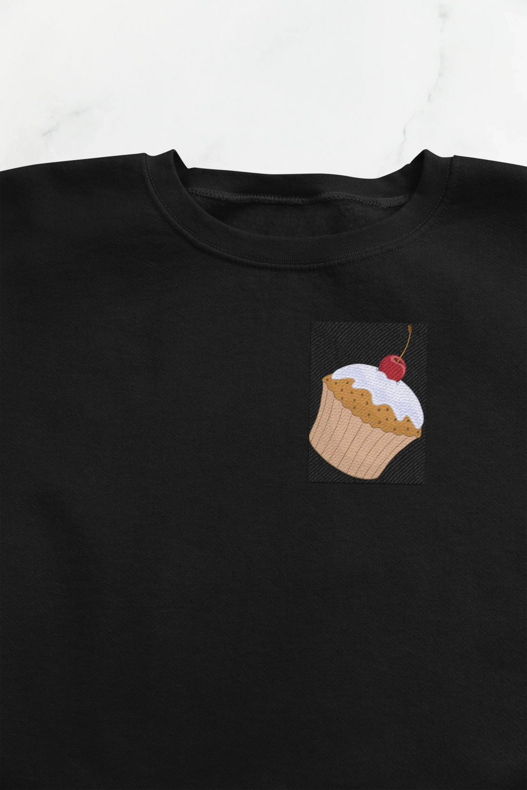 Black crewneck cupcake sweatshirt with small cupcake graphic patch on chest