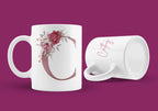 White ceramic mug with floral letter C design and pink script on front, side handle visible