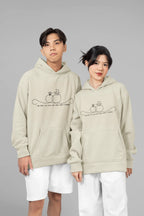 Light beige unisex hoodies worn together; front pocket and line-art wedding rings graphic.