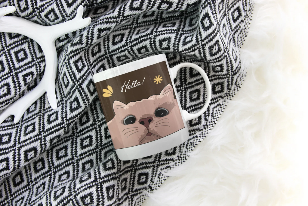 White ceramic mug with cat face and 'Hello!' text graphic on front