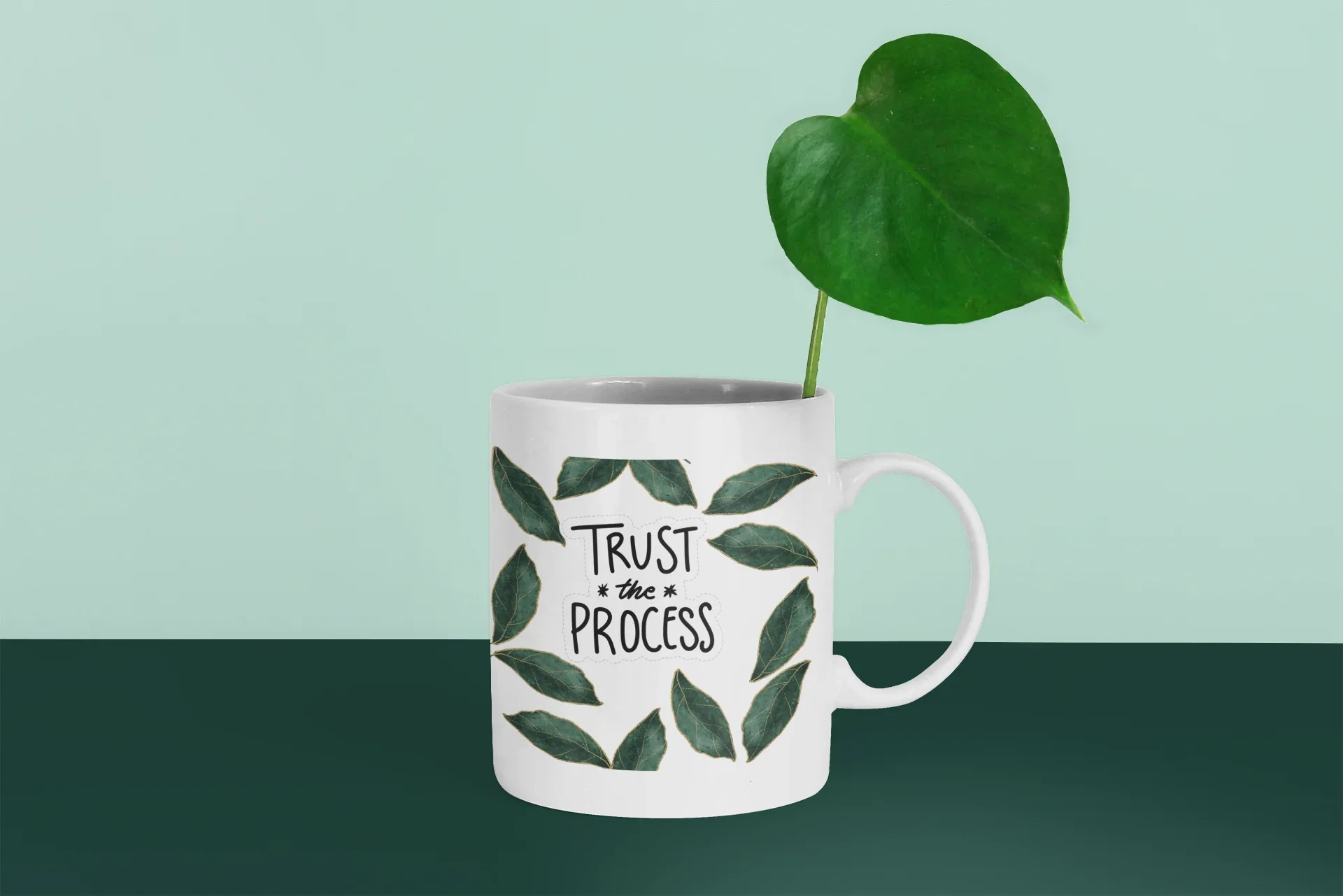 White 11oz coffee mug with green leaf design and “Trust the Process” on the front