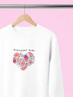 White sweatshirt with “BIRTHDAY GIRL” text and floral heart graphic on the chest