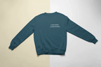 Teal crewneck sweatshirt with "a year wiser, a world kinder" text on chest