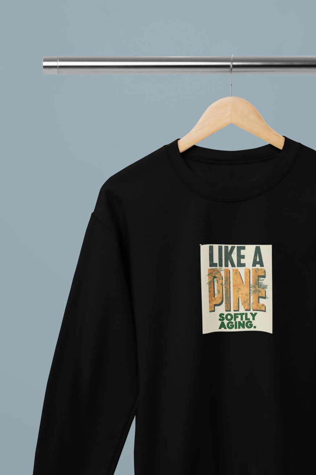 Black crewneck sweatshirt with square front graphic print on a wooden hanger