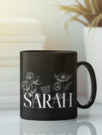 Black ceramic mug with floral line art and name SARAH on front