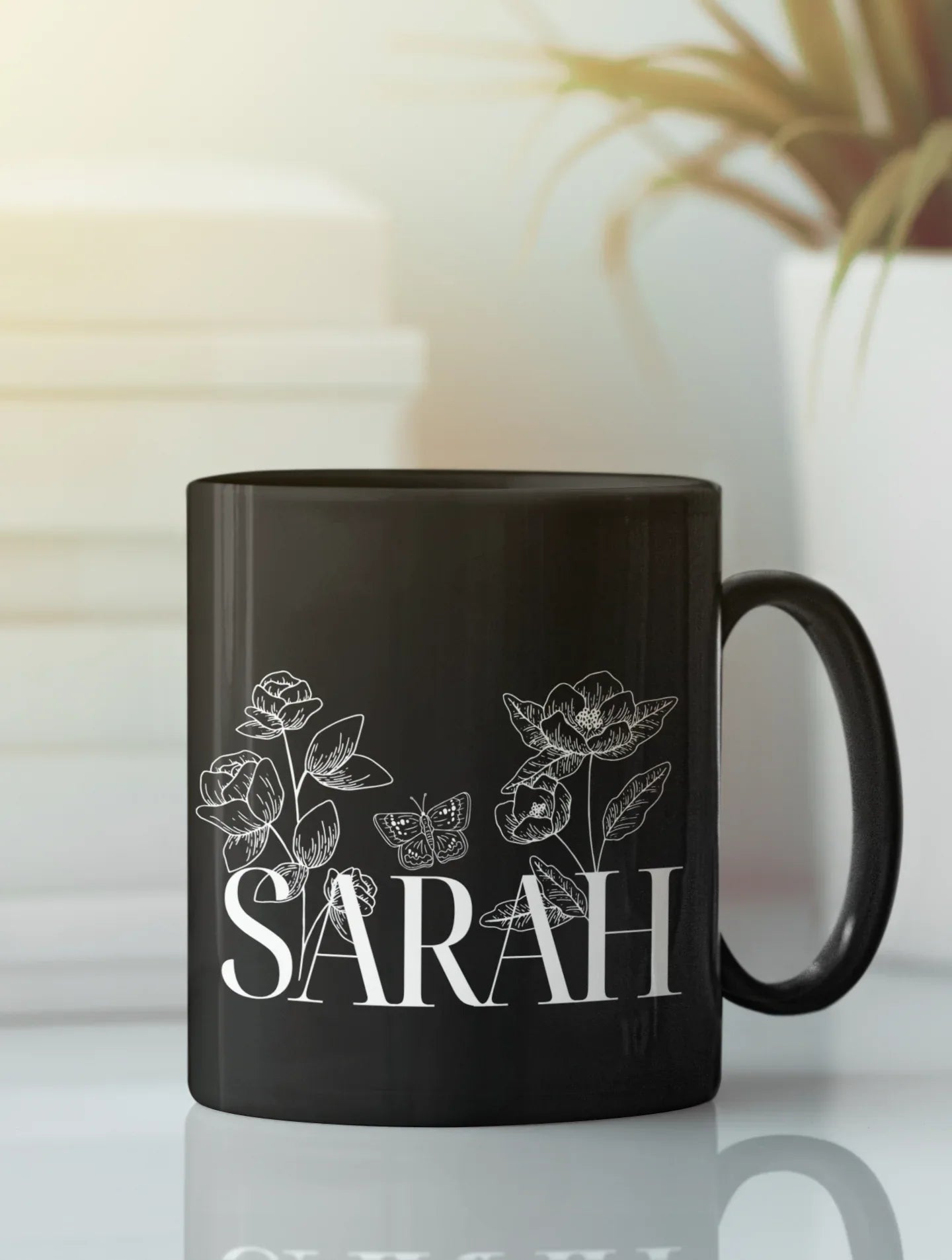 Black ceramic mug with floral line art and name SARAH on front