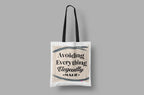 White canvas tote bag with black handles; reads “Avoiding Everything Elegantly”