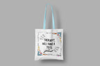 Flat-lay white tote bag with blue handles, printed quote and colorful doodle border.