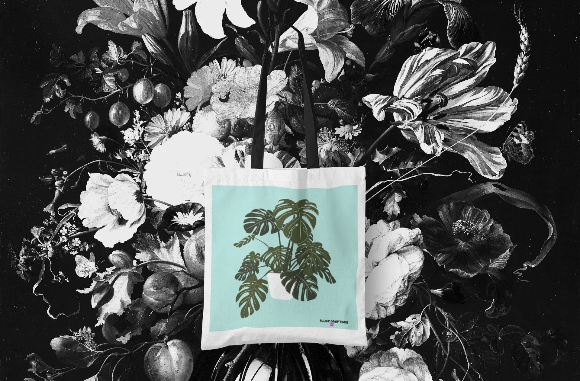 White tote bag with black handles and green monstera leaf artwork