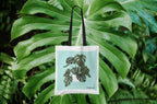 White tote bag with black handles and green monstera leaf print on front