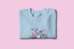 Light blue floral crewneck sweatshirt with colorful garden graphic on front
