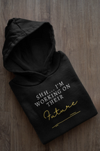 Black hooded sweatshirt, folded, with 'Future' script and 'I'm Working on Their' text