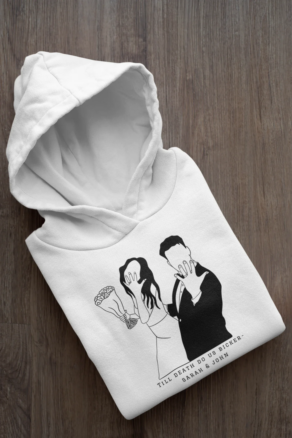 Folded white hoodie with black couple graphic and text, hood and long sleeves.