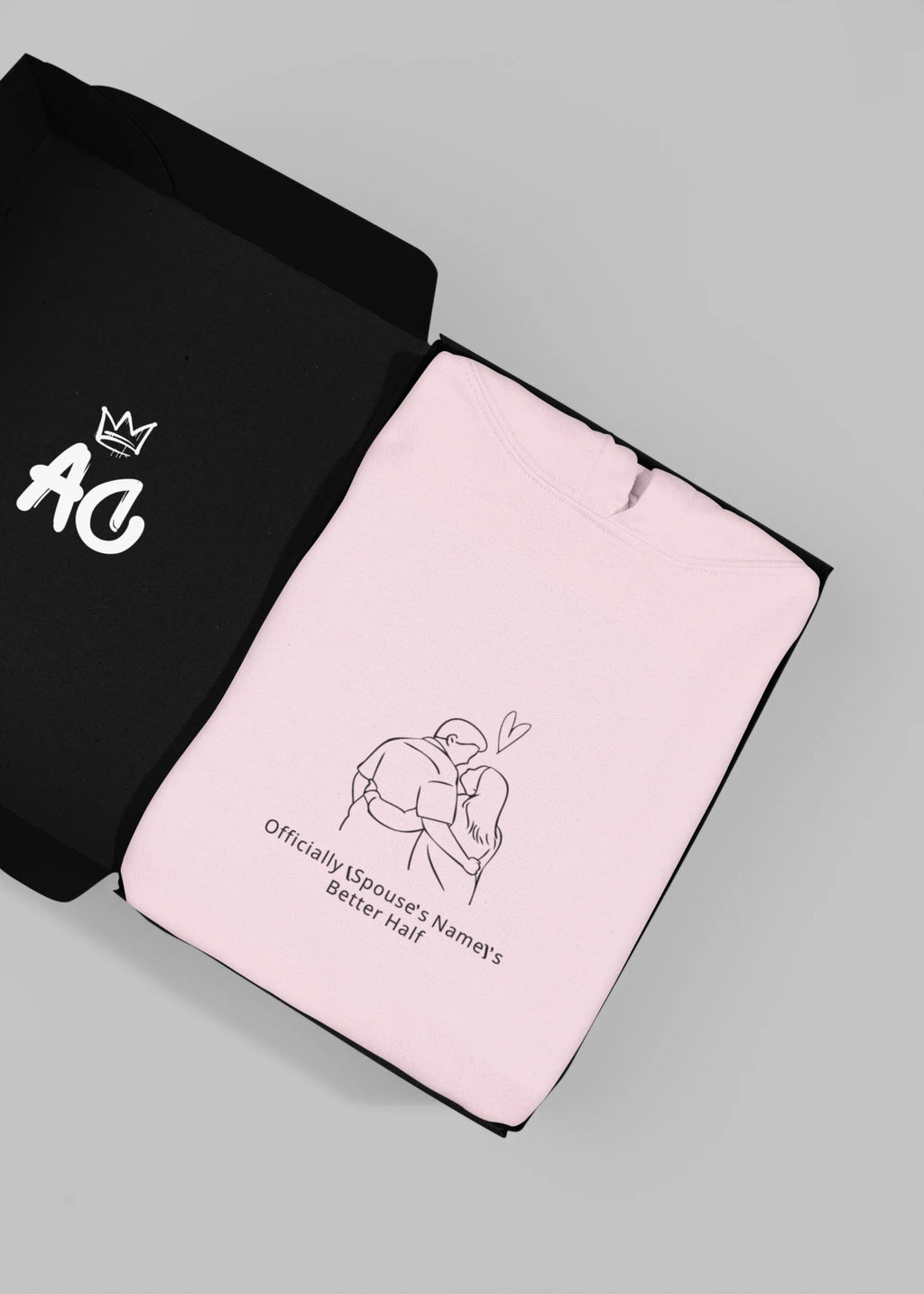Light pink hooded sweatshirt folded flat with couple graphic on center