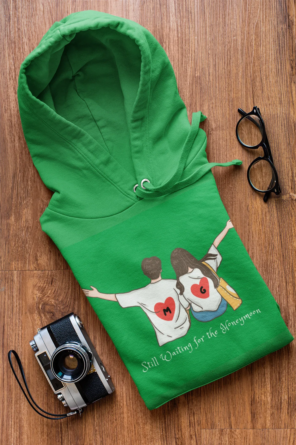 Green hoodie with couple heart graphic and 'Still Waiting for the Honeymoon' lettering.