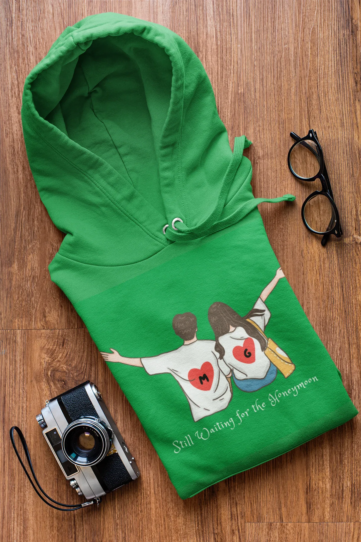 Green hoodie with couple heart graphic and 'Still Waiting for the Honeymoon' lettering.