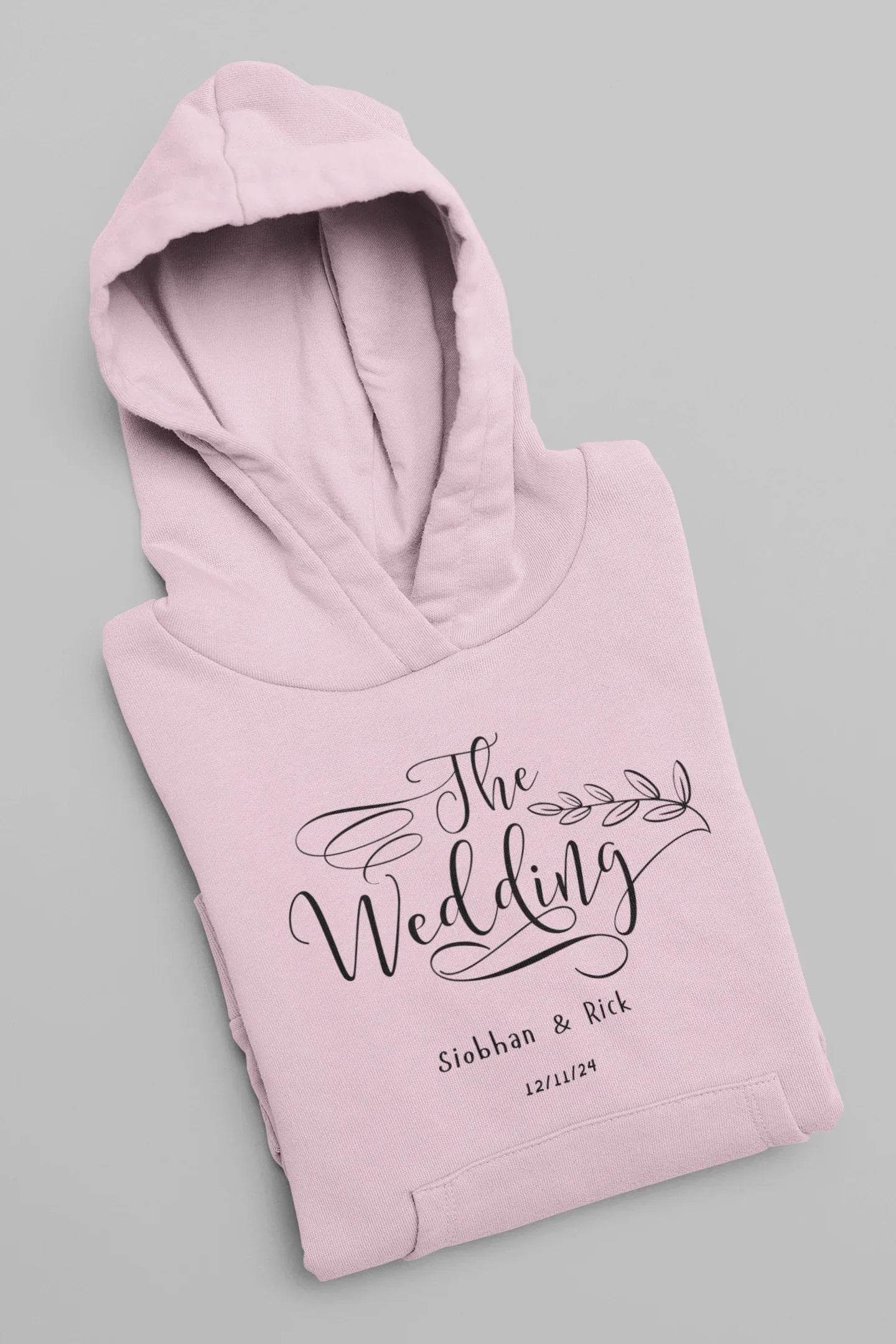 Light pink wedding day hoodie sweatshirt with “The Wedding” front logo and hood
