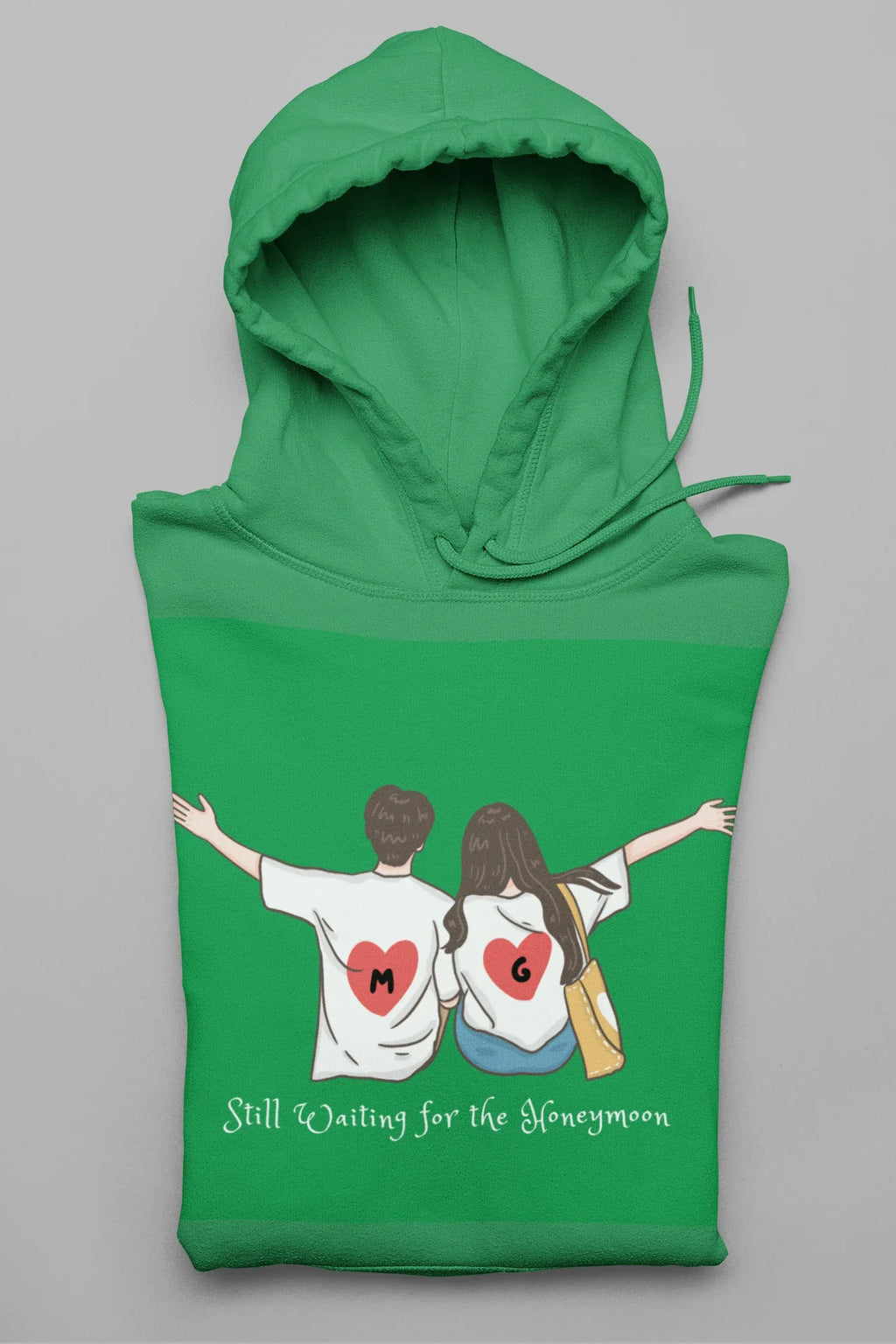Green hoodie with hood and front pocket, featuring couple heart graphic and text.