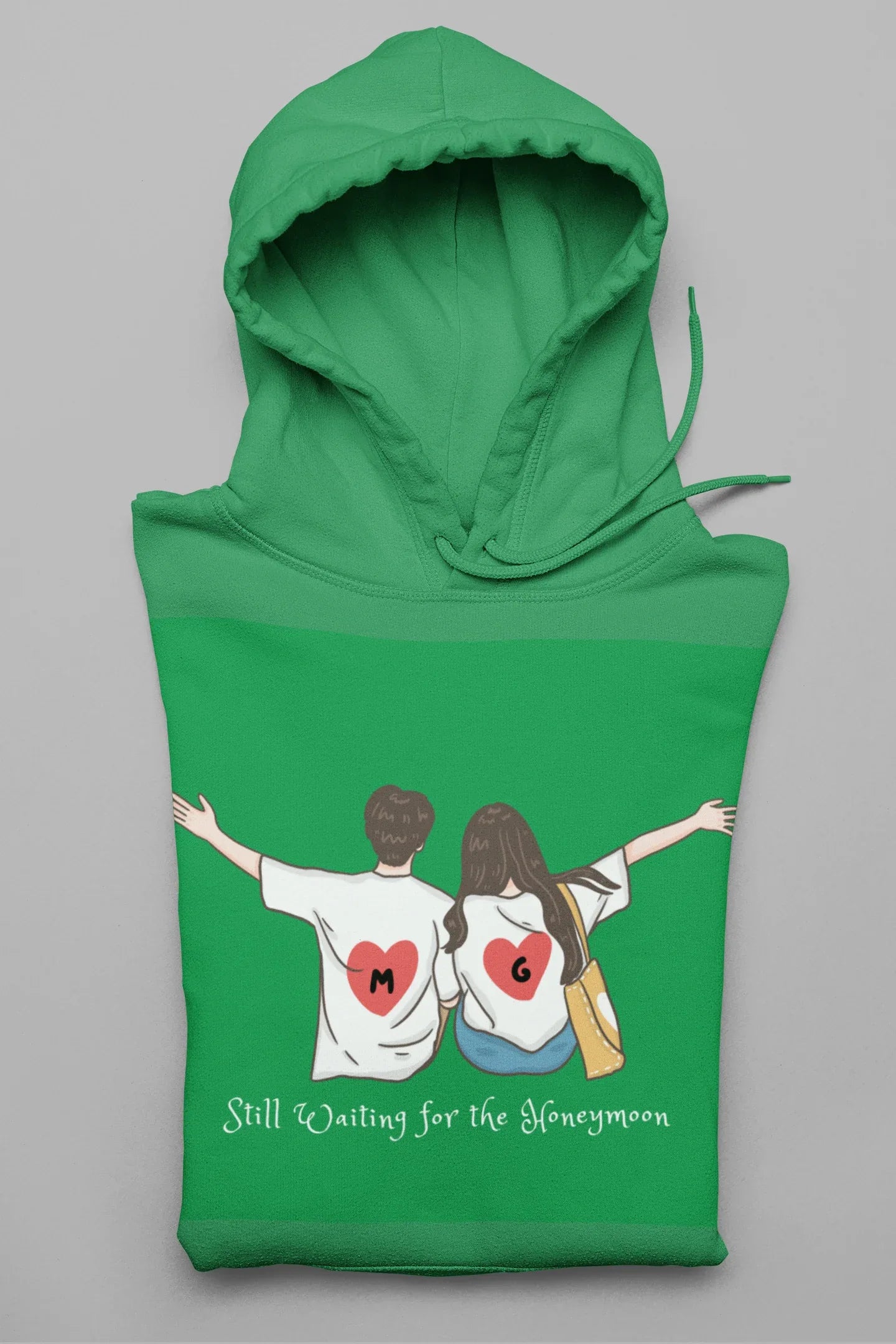 Green hoodie with hood and front pocket, featuring couple heart graphic and text.