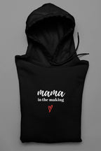 Black hooded sweatshirt with 'mama in the making' logo and red heart