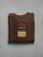 Brown birthday cake sweatshirt with front "Happy birthday" and lit candle cake graphic.