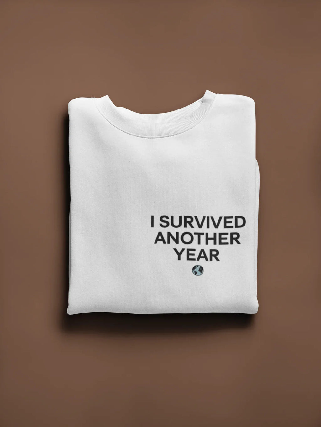White crewneck sweatshirt with front text graphic “I SURVIVED ANOTHER YEAR” and small icon