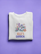 White crewneck sweatshirt with floral crest and 'Nelly's Garden' print.