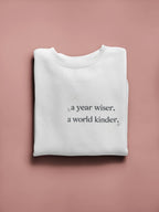 White crewneck sweatshirt with a year wiser, a world kinder print
