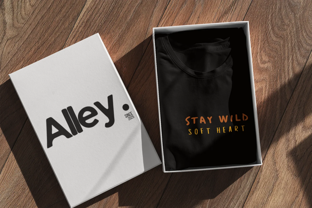 Black hoodie laid in open box, showing Wild West emblem and Stay Wild Soft Heart text